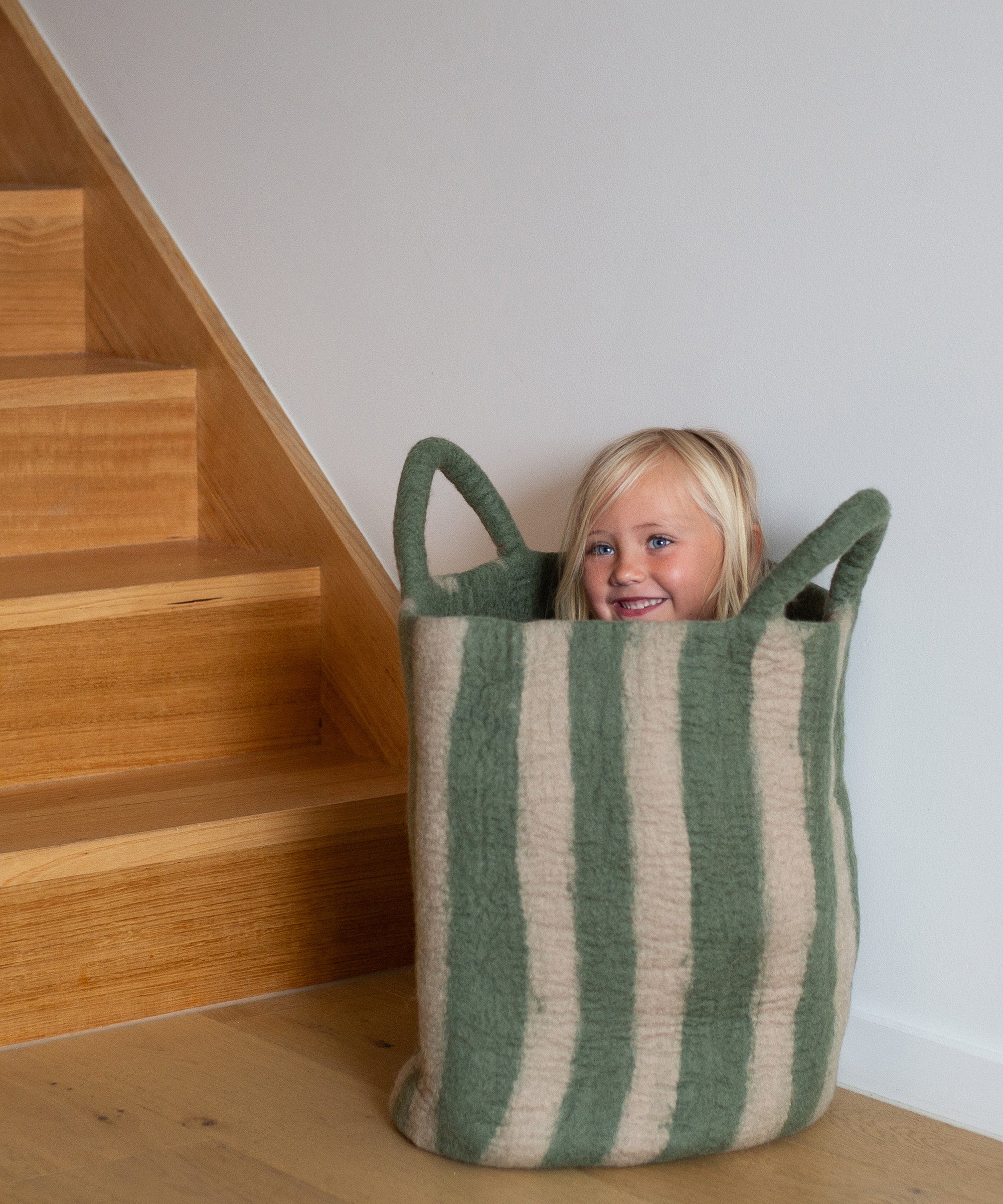 child in striped green toy basket